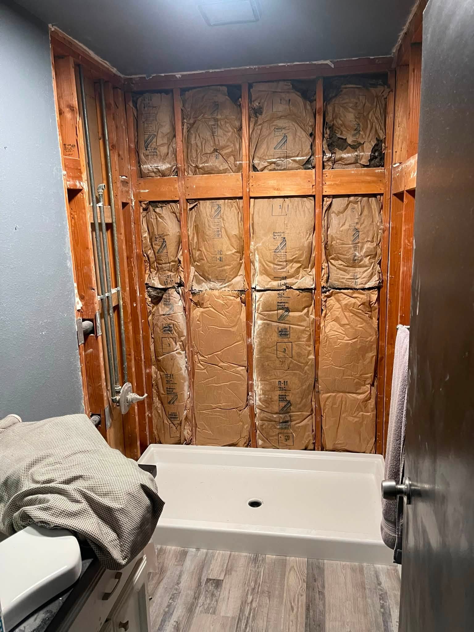 Bathroom shower renovation in progress with plumbing wall exposed