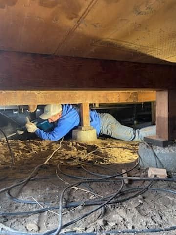Plumber working beneath a home in a crawlspace
